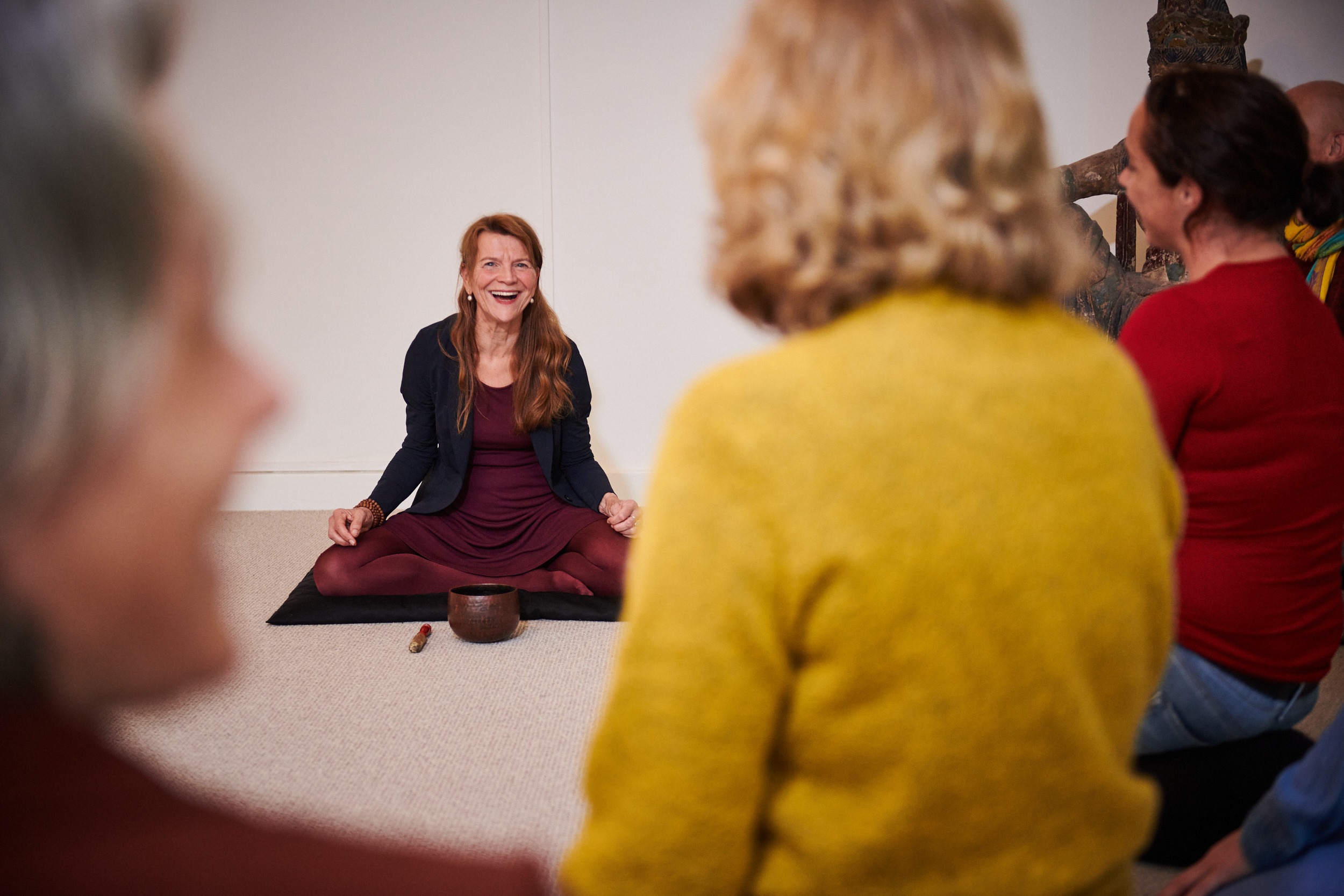 Vrouw mediteert in kleermakerszit met een klankschaal tijdens een meditatiebijeenkomst bij de School voor Zijnsoriëntatie